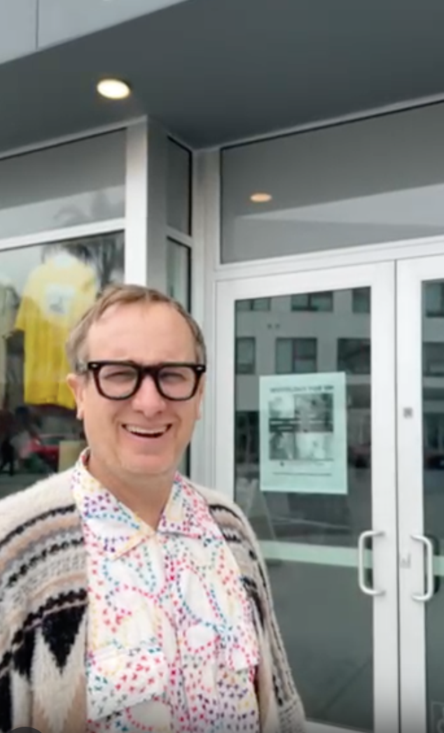 Client giving a testimonial about successful licensing support from Anshin Mobile Notary & LiveScan, standing outside office entrance.